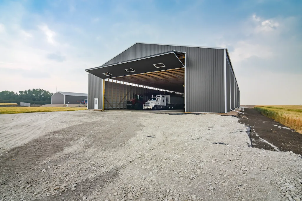 Full opened bi-fold door reveals the interior of a large post frame agricultural storage building