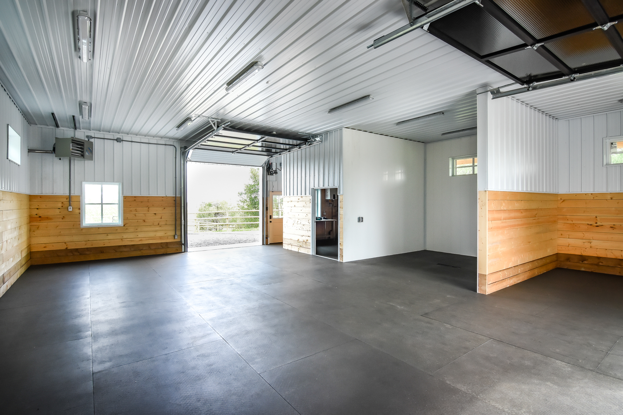 Interior of a custom horse shelter finished interior, featuring a concrete floor, kick wall, and metal cladding.