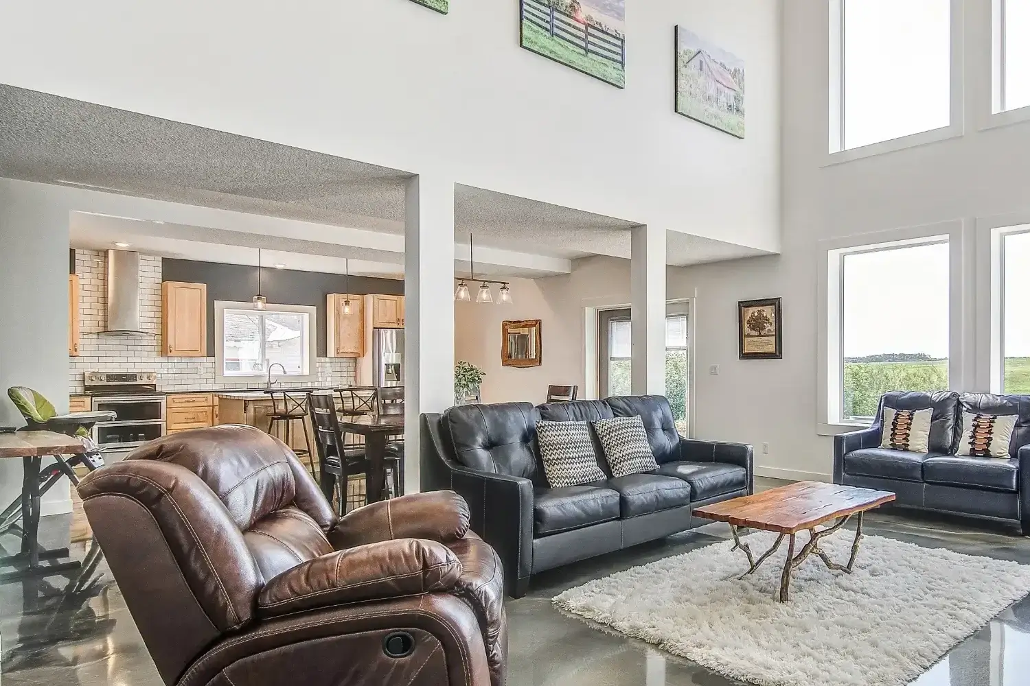 Bright and modern barndominium interior with open concept layout, large windows, and polished concrete floors.