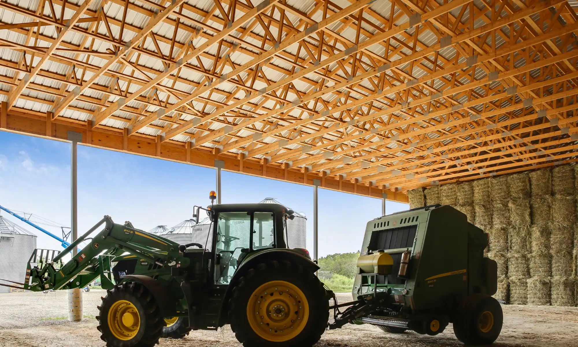 Open-sided hay storage shelter with horse feed storage and farm equipment