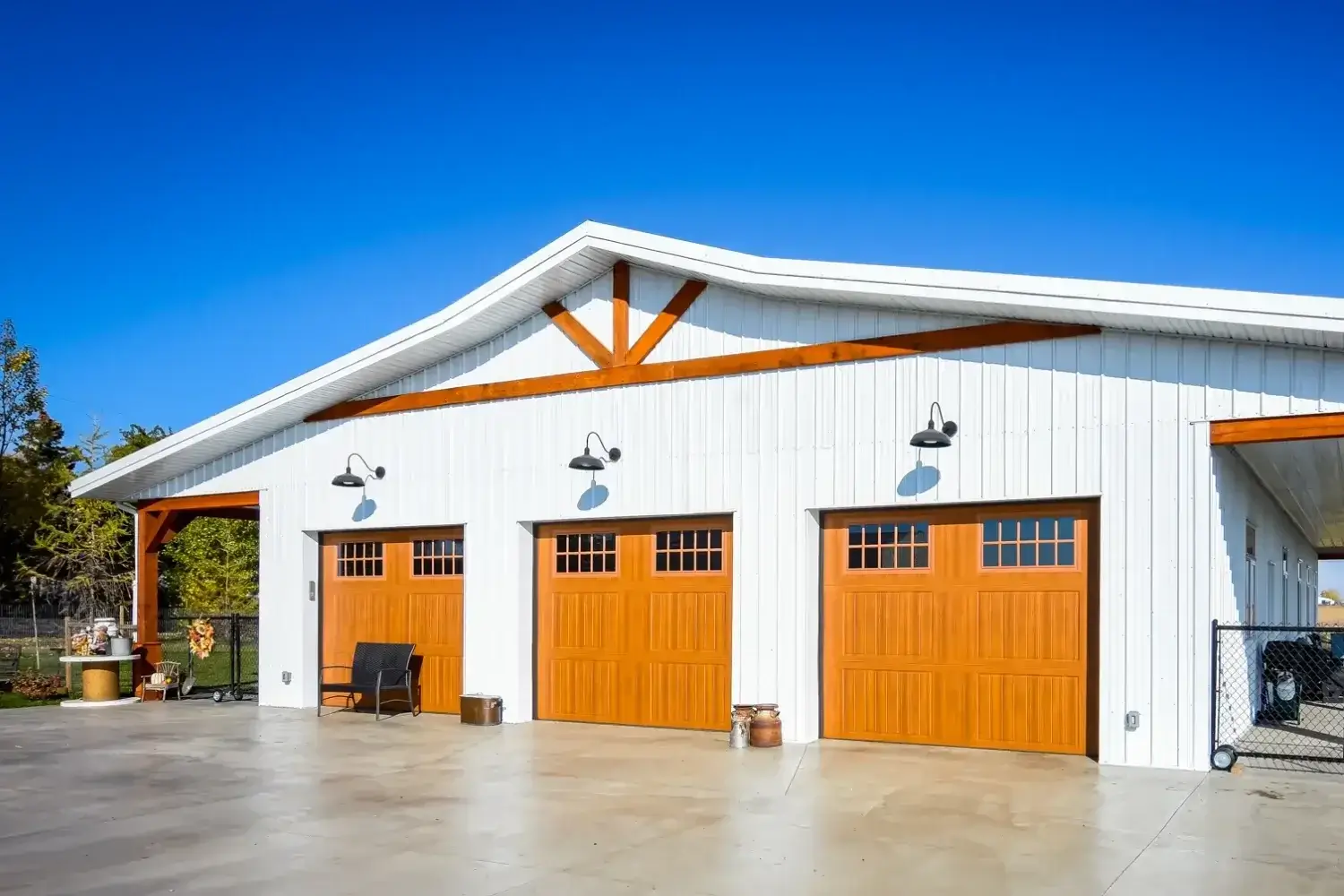 White barndominium shop home with wood-tone garage doors and spacious shop area.