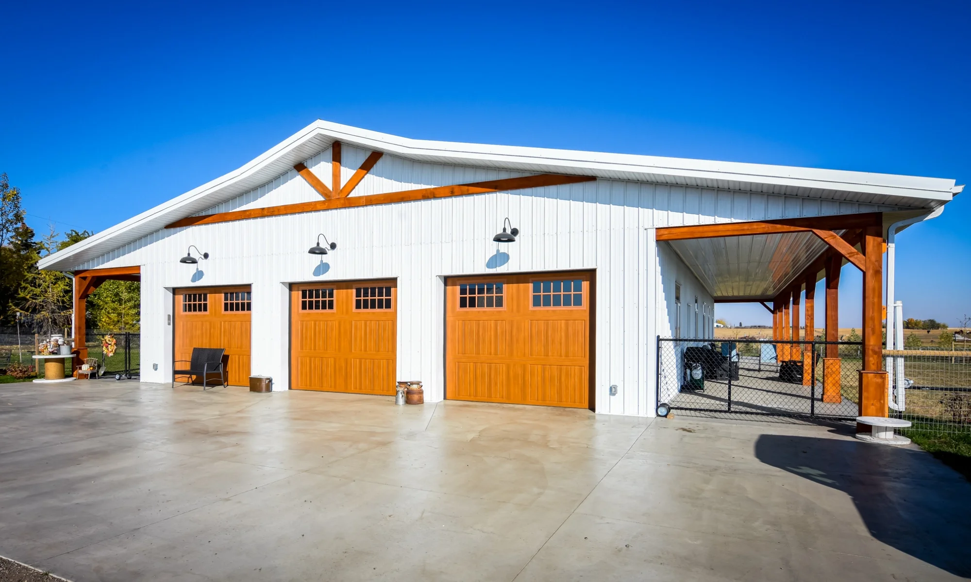 White barndominium with wood-tone garage doors and spacious shop area.