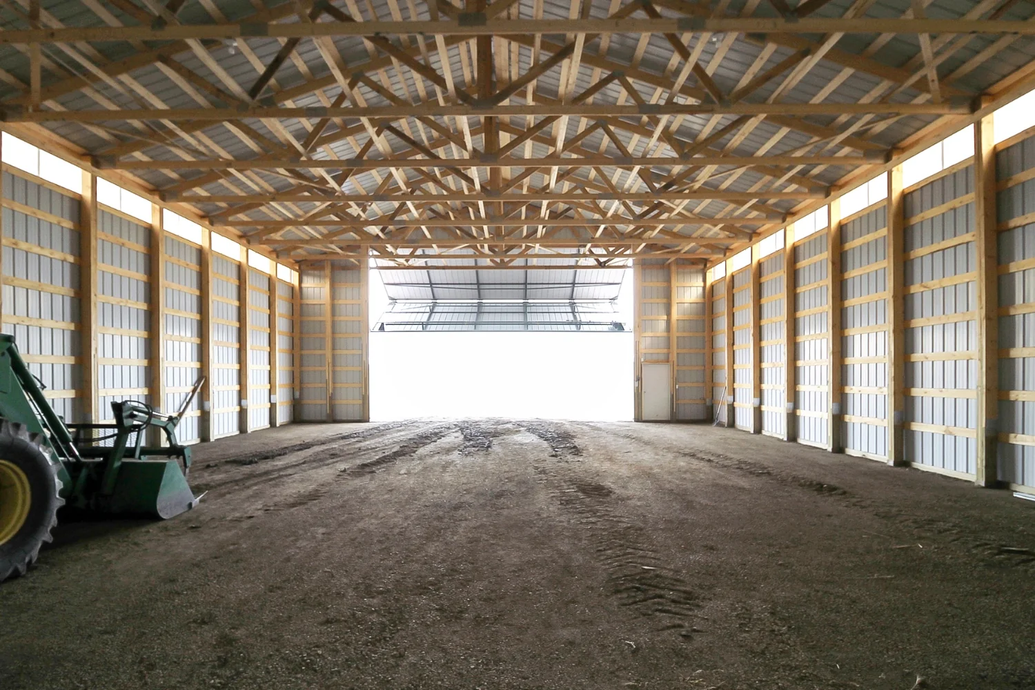 Unfinished machine shed for farm equipment storage shows the function of a bi-fold door.