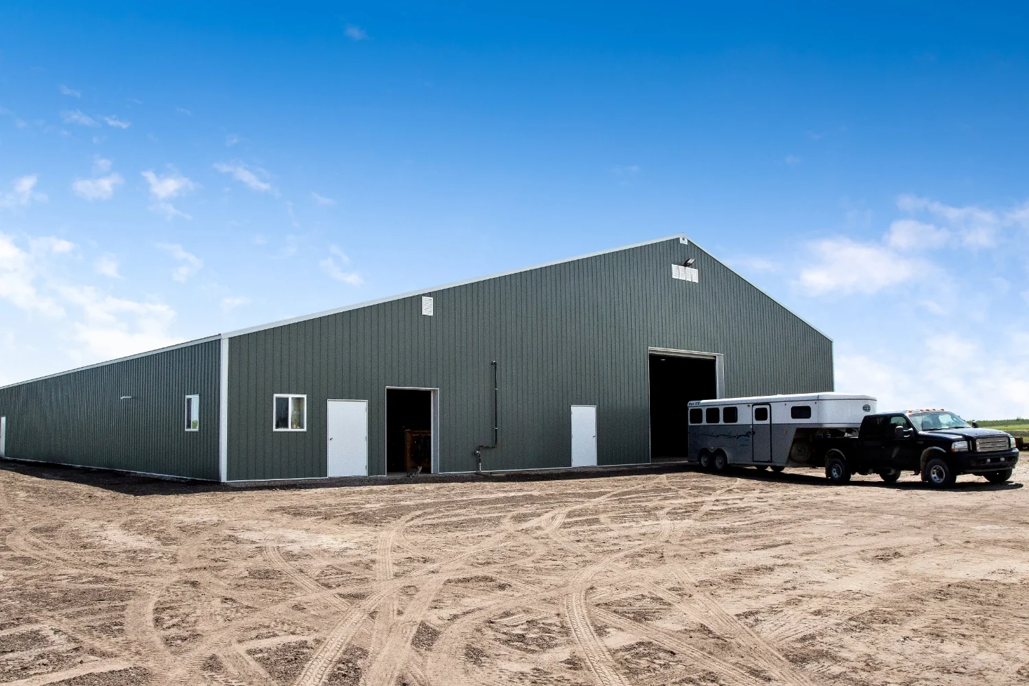 Custom riding arena exterior was designed to accommodate equipment, horse, and rider access with a variety of overhead doors.