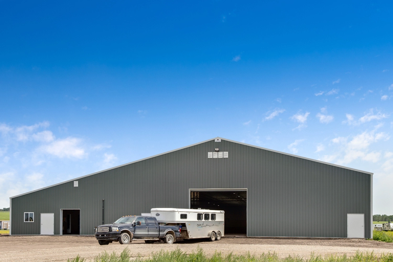A horse trailer backed up to an indoor horse riding arena, ready to offload.