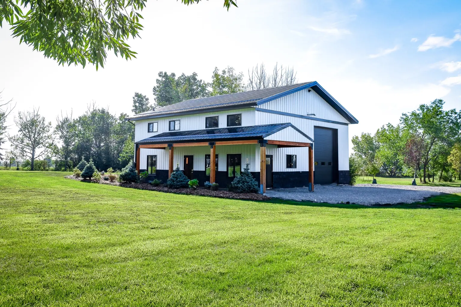 Custom pole barn building hobby shop with metal siding, front porch, guest quarters, and upper-level recreation space.