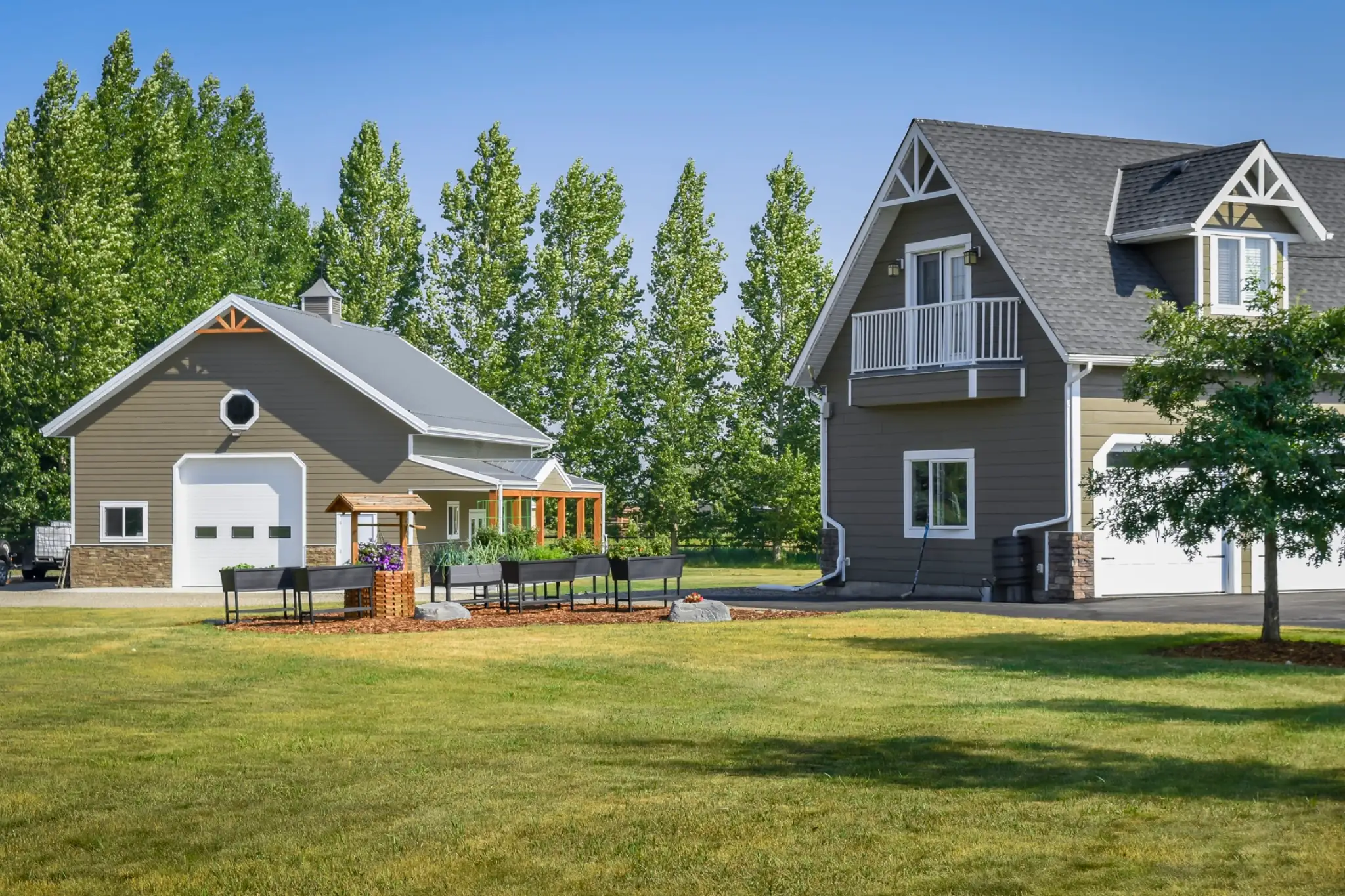 Sitting next to an acreage home, a post frame garage shows careful design to match the overall aesthetic of the home.