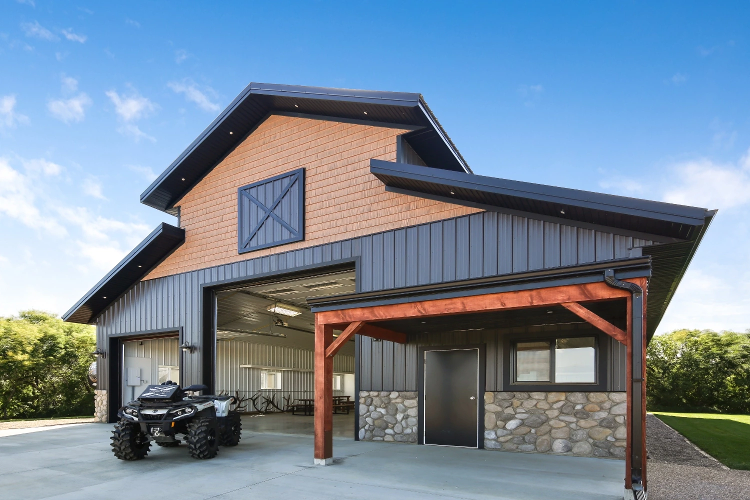 Craftsmanship and design excellence shines through in a close-up of a monitor-style shop. Featuring a porch, faux hay door, and stone wainscoting for a premium appearance.