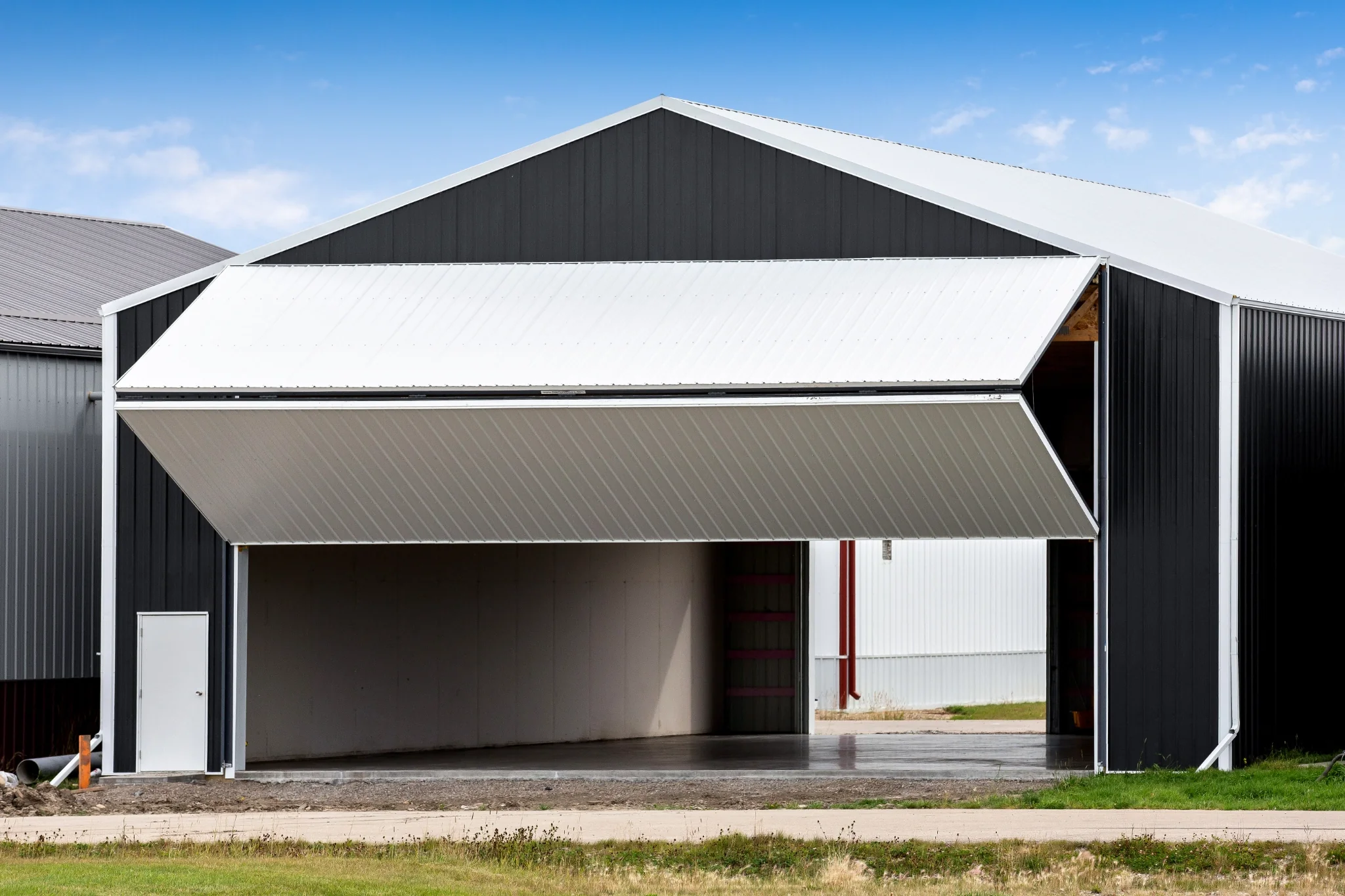 A simple post frame airplane hangar at an rural airport with a partially open bi-fold door.