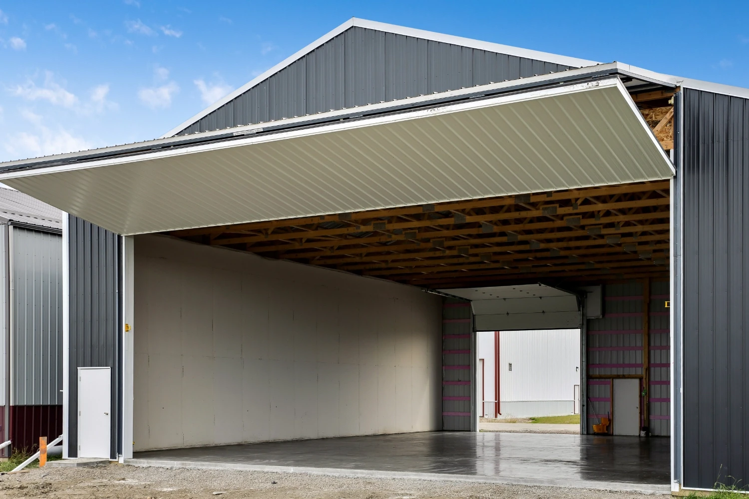 A grey and white aircraft hangar built with post frame construction to create a clear-span interior to accommodate small aricraft.