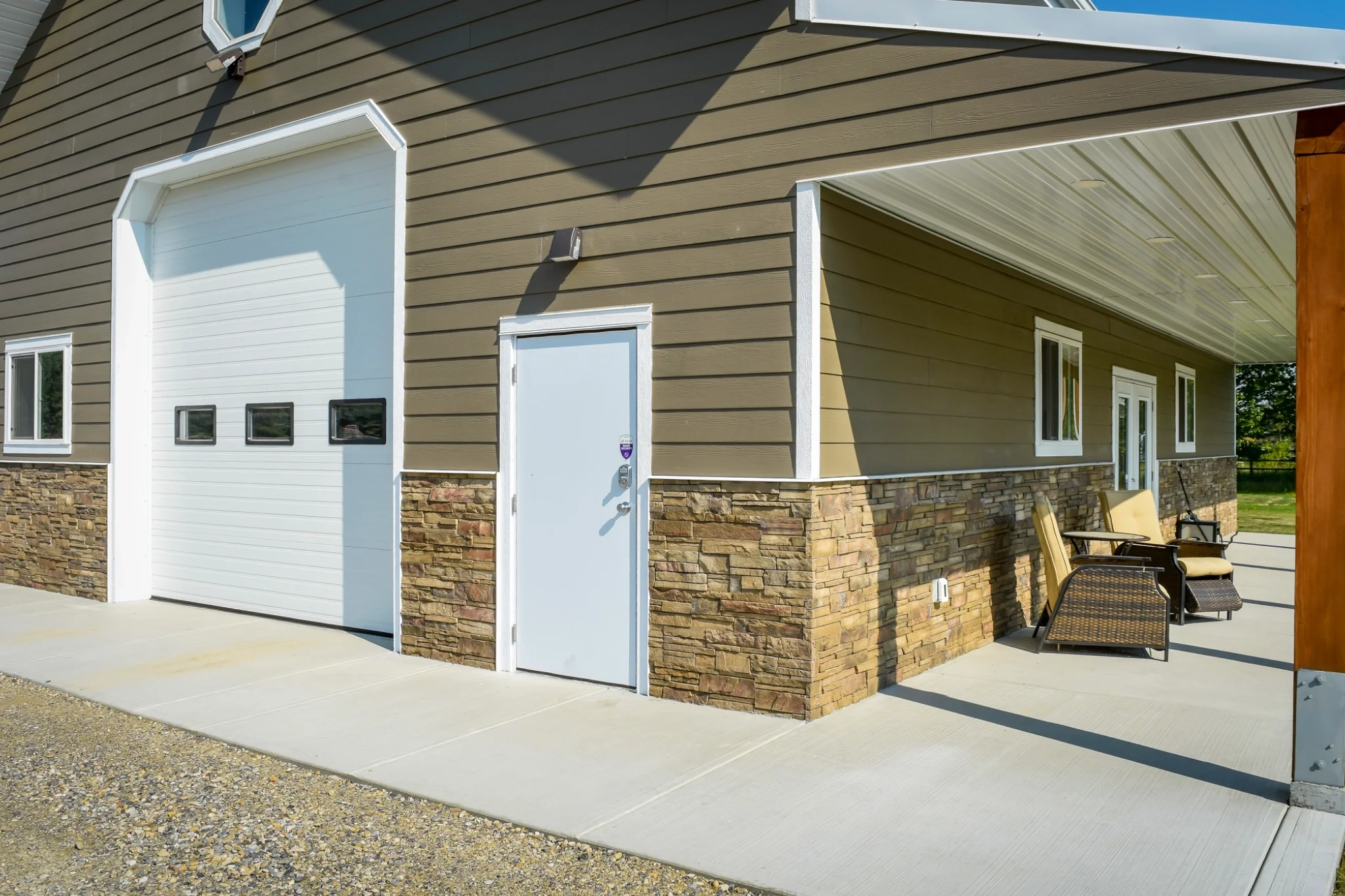 A close up of a post frame garage show some key differences between typical post frame buildings by using hardie board and a stone wainscoting.