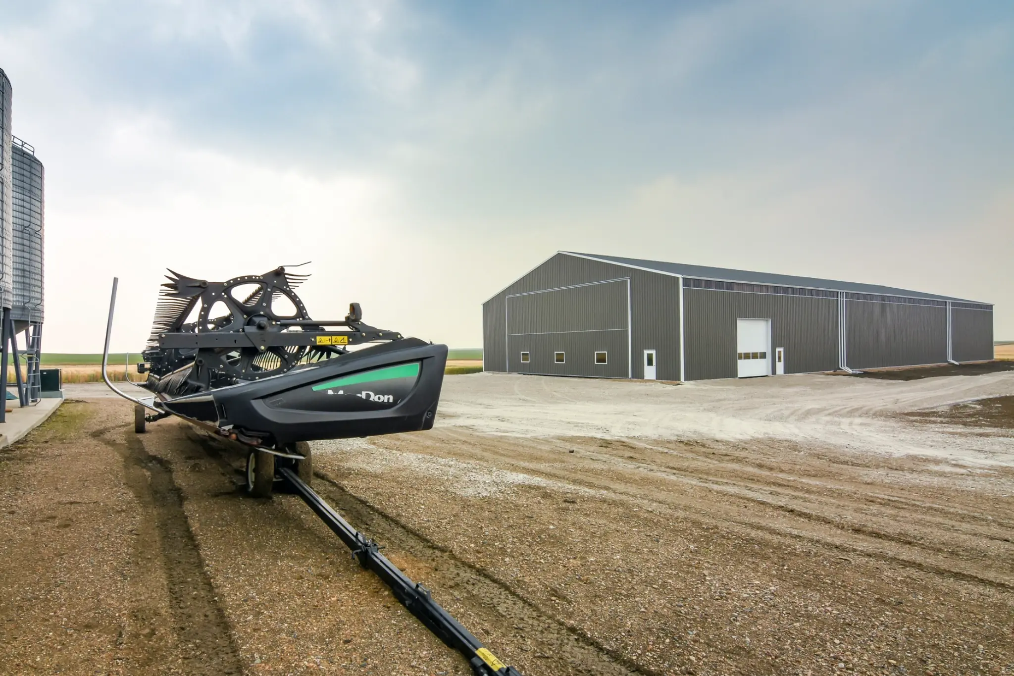 Farm implements sit outside a post frame cold storage building, creating a scenic photo.