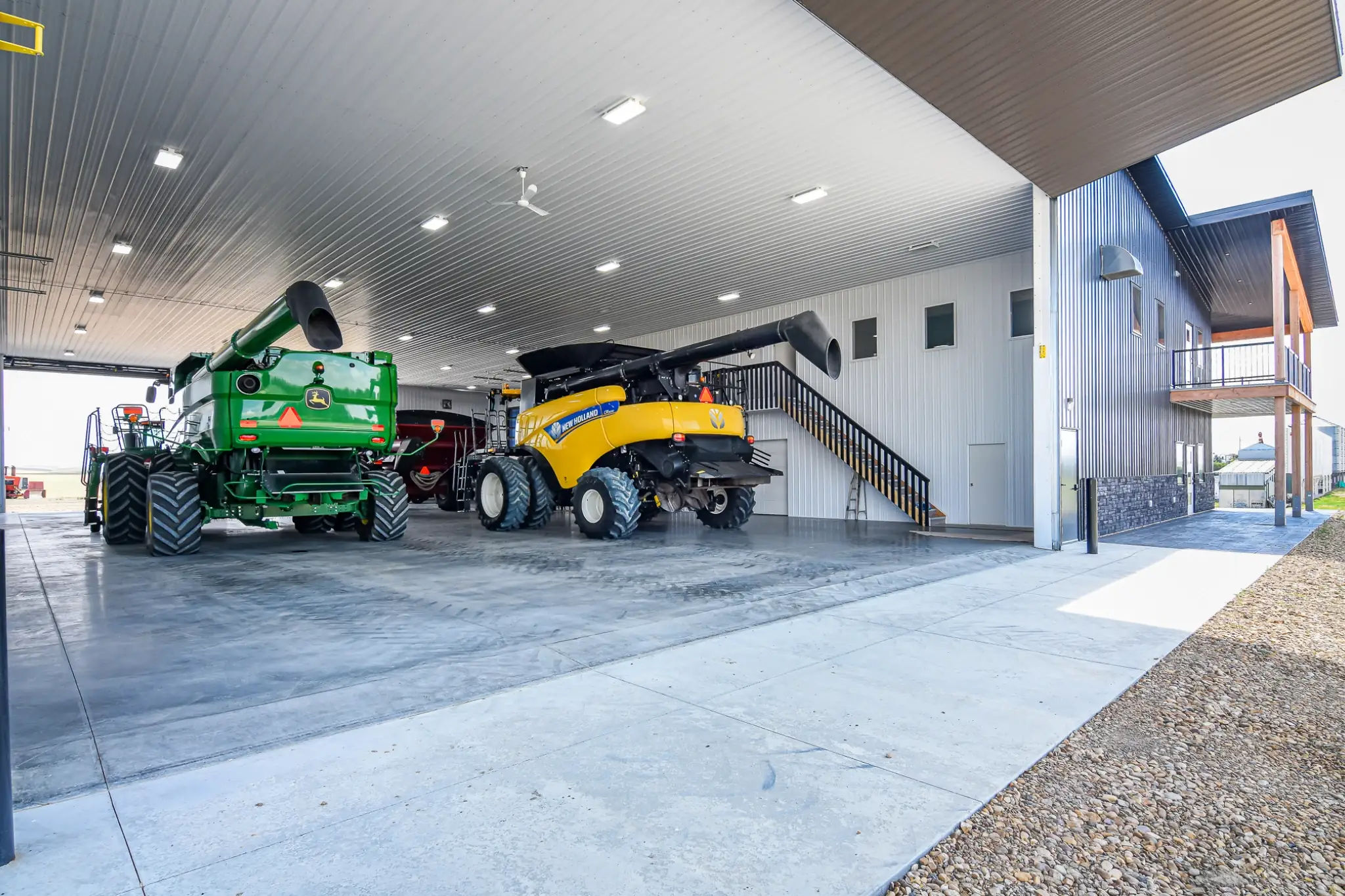 A range of combines, tractors, and equipment sit in a fully finished agricultural building.