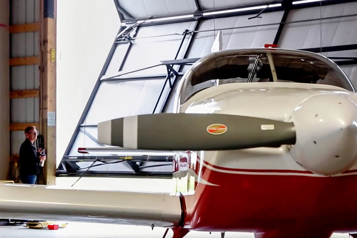 A plane inside a post frame hangar with a bi-fold door.