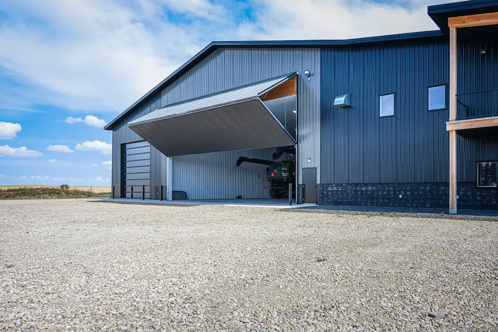 Exterior of a post frame farm shop with premium features like stone wainscoting and wrap around porch