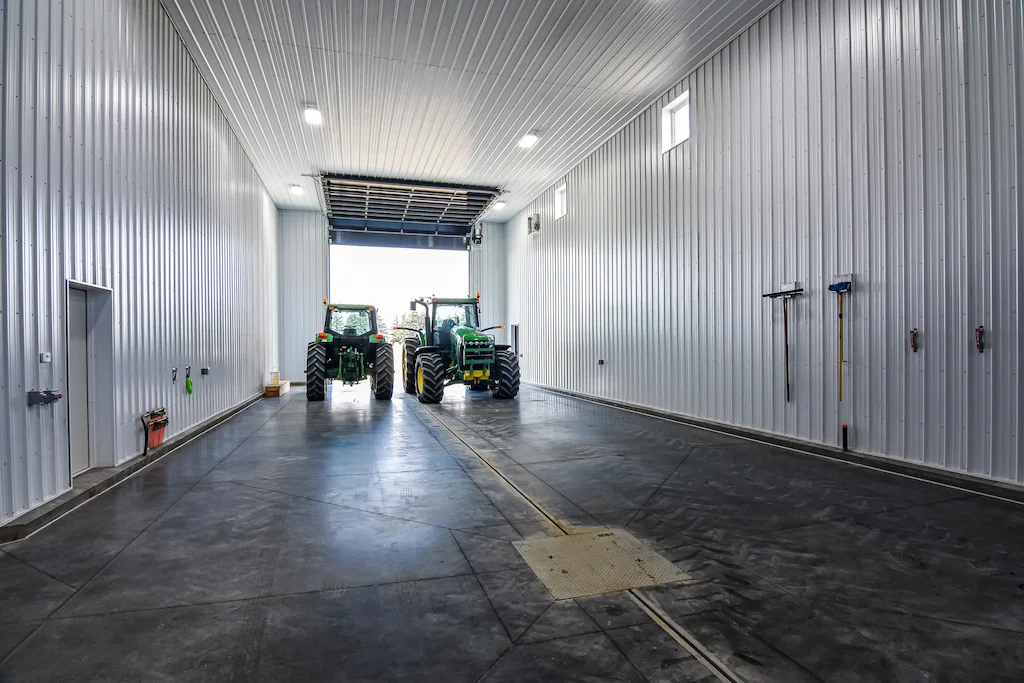 Two tractors inside the wash bay section of a large, heated farm shop