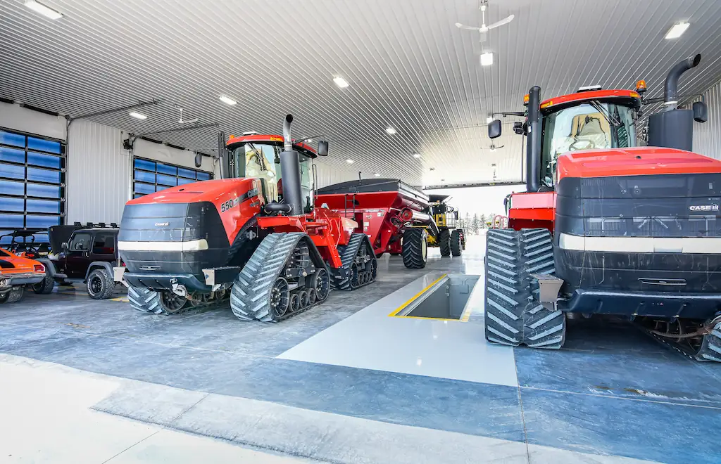 Fleet of farm equipment inside an agricultural workshop with office and wash bay