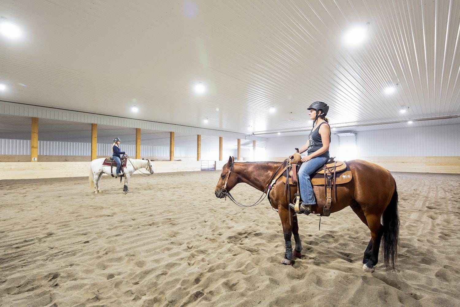 Riders taking part in an equestrian lesson in a heated horse arena