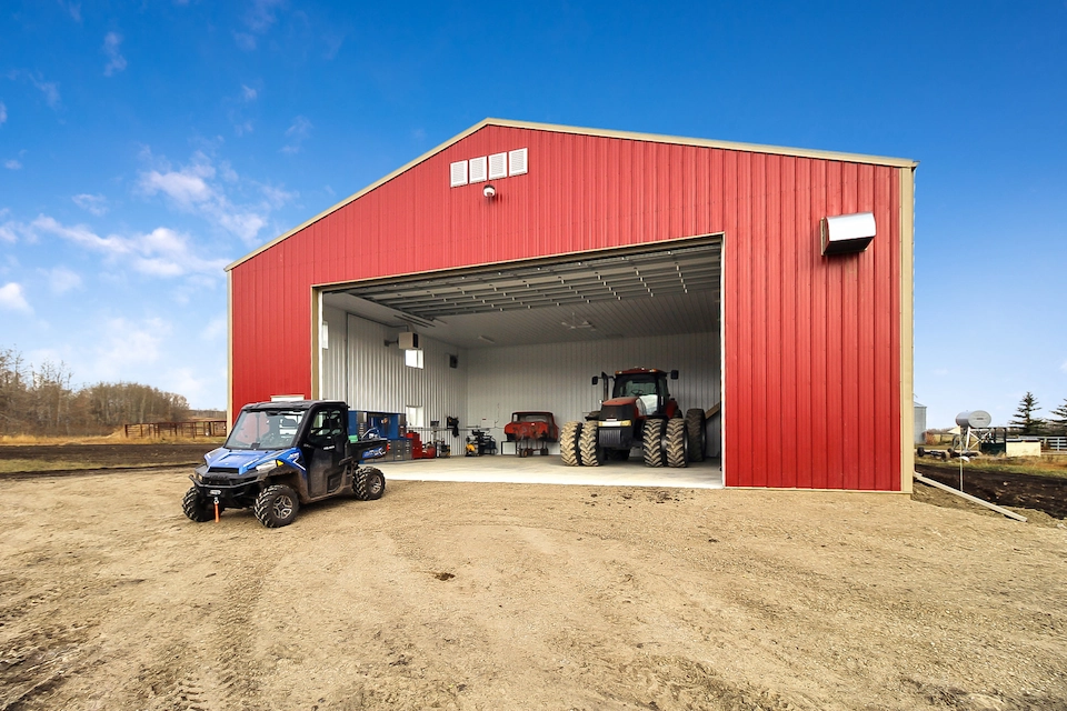 Farm building with open equipment door, showing the insulated interior and machinery inside