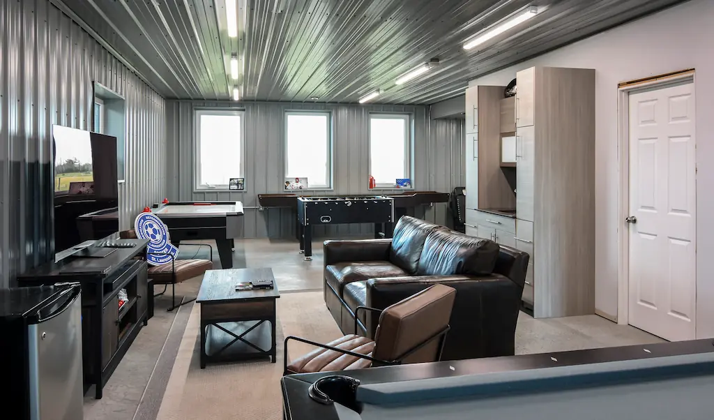 Lounge and recreation area in a post frame shop with couches, tv, and games tables