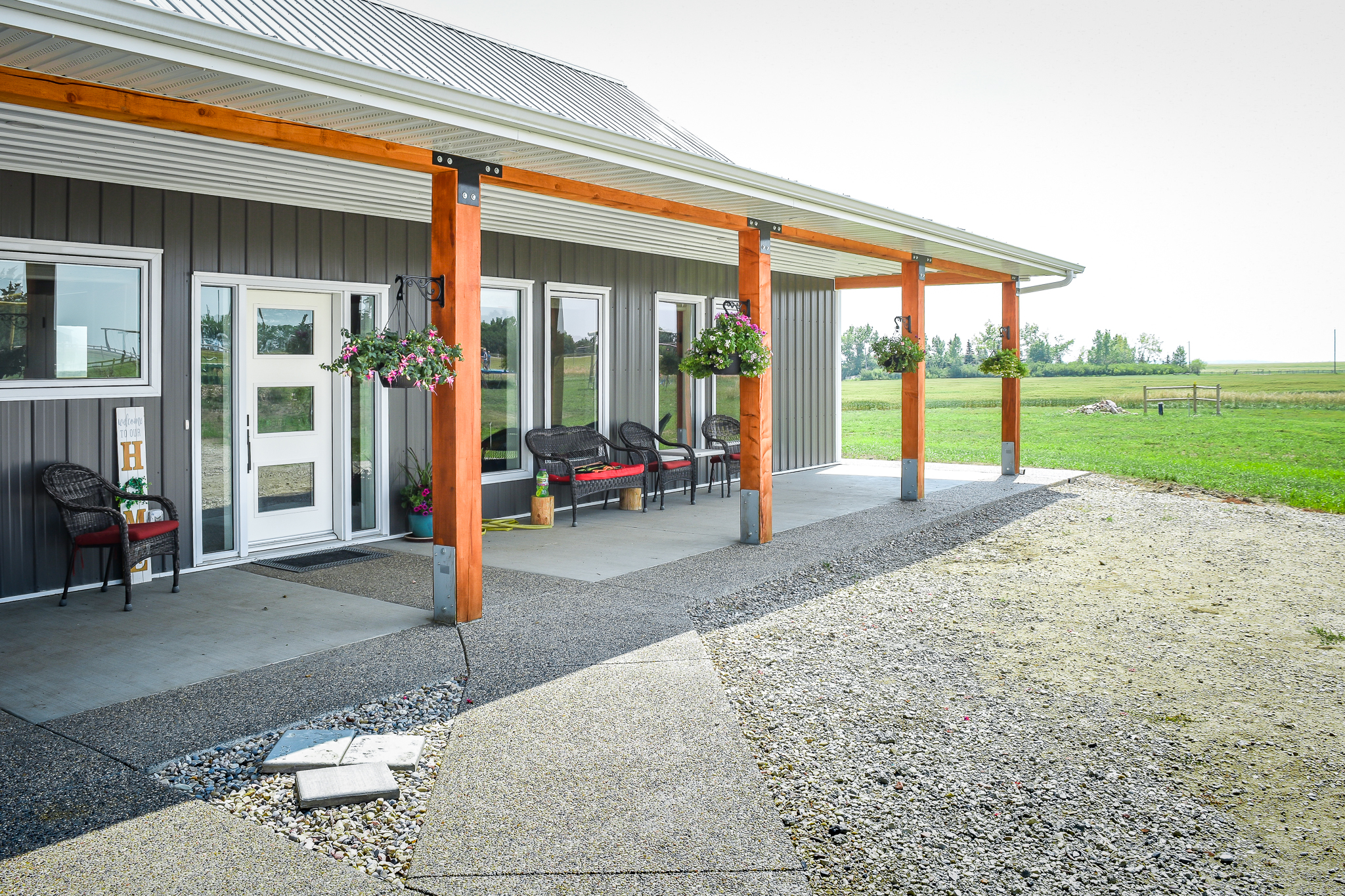 The front entrance of a post frame bungalow is covered by a roof supported with exposed posts and beams.
