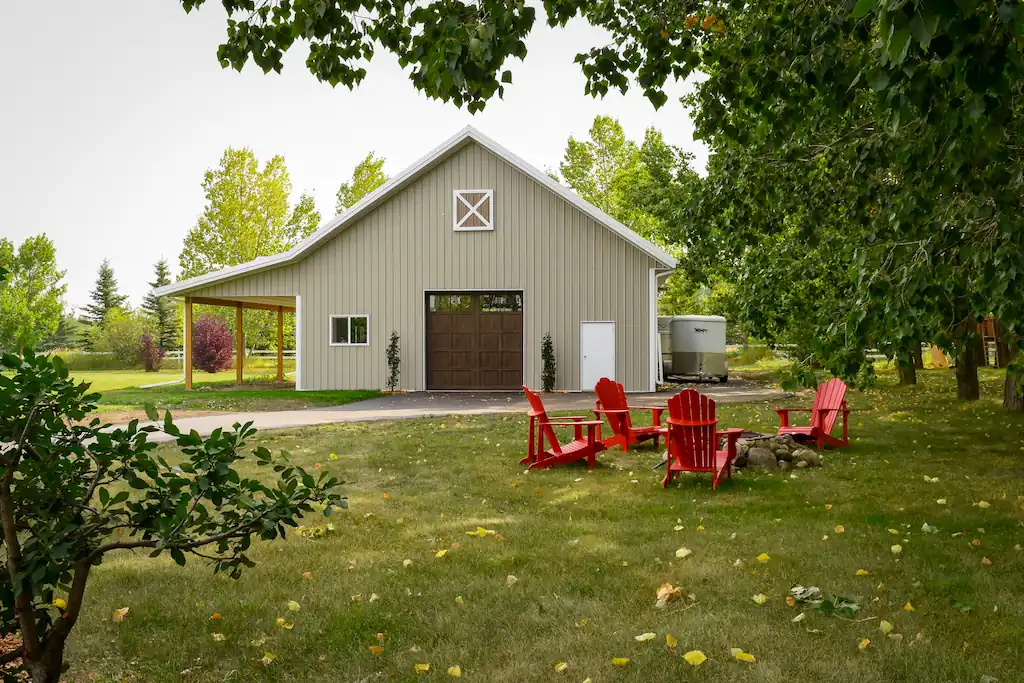 Exterior of a small custom horse barn with a lean-to and carriage door
