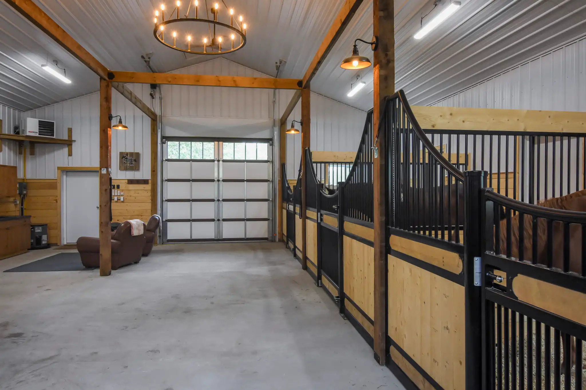 Interior of a small post frame horse barn with three stalls is finished with a kick wall