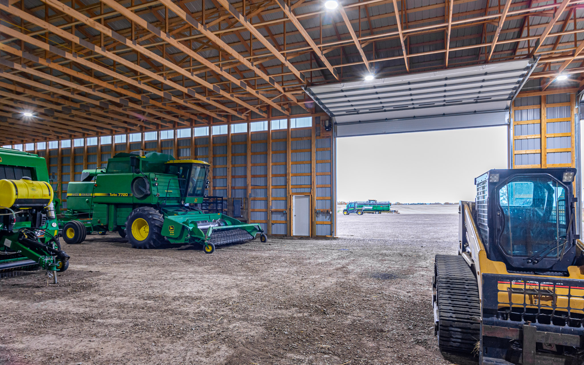 A John Deere combine sits inside a post frame cold storage for protection against harsh weather