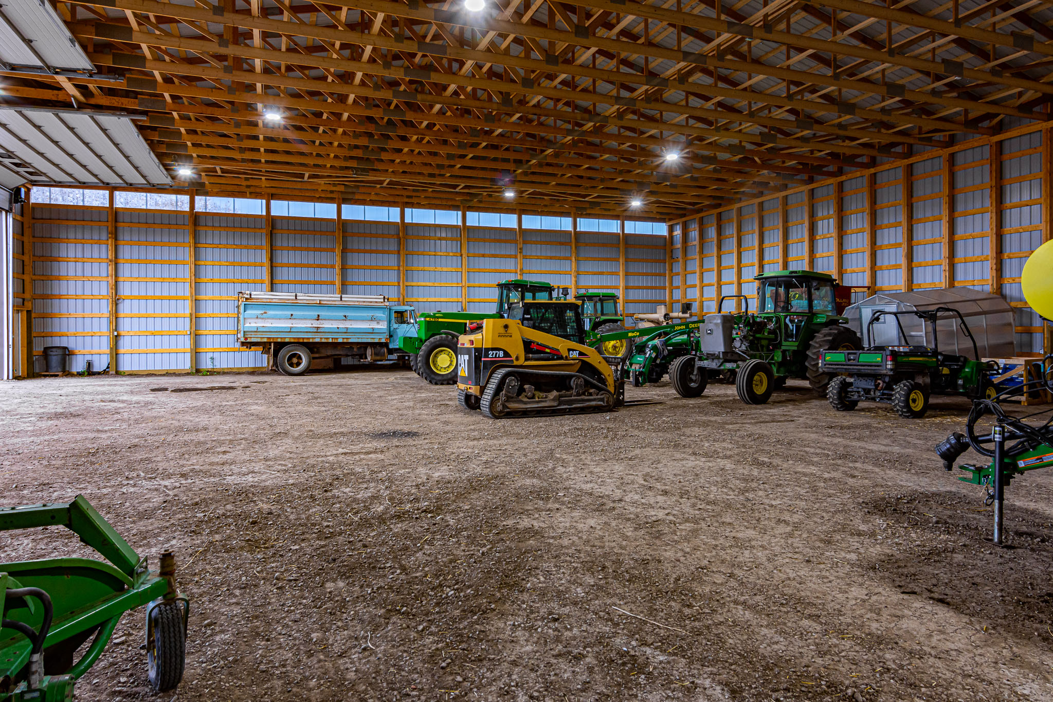 A full fleet of farm implements sits in side an agricultural cold storage building