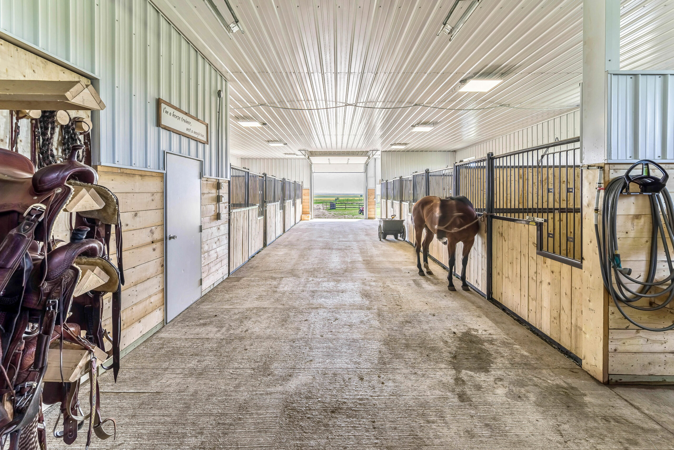 Interior of a fully finished horse barn with stalls, a kick wall, wash bay, and a tack room