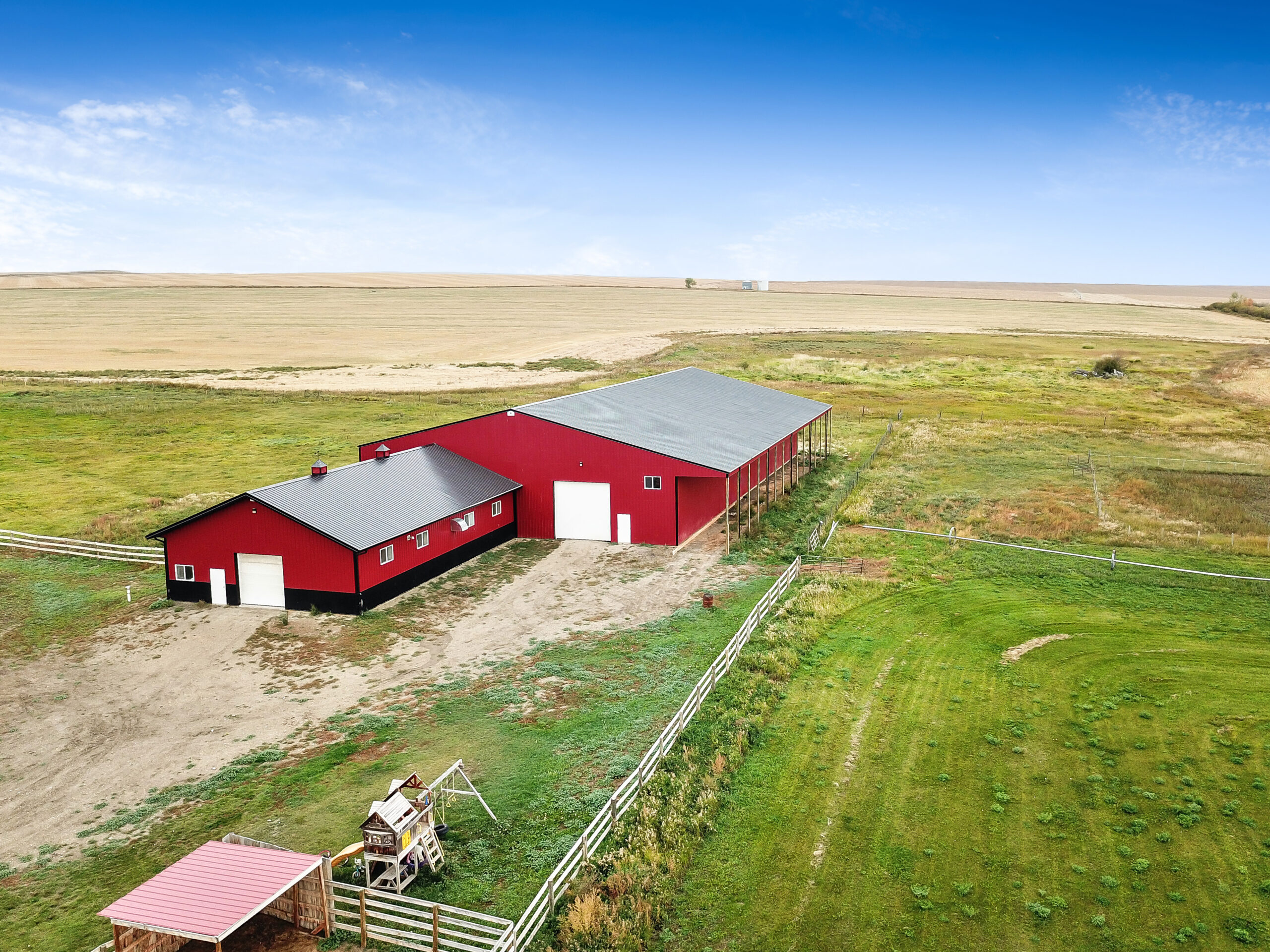 Exterior of a red and black horse barn and riding arena combining to make the ultimate equestrian facility.