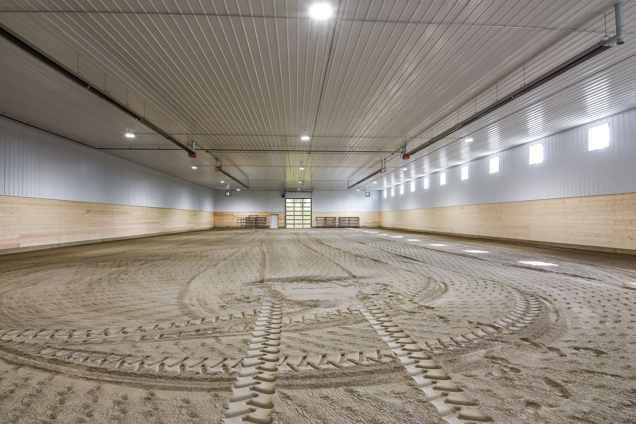 An indoor horse riding arena with a 8' tall kick wall to protect both horses and the structure