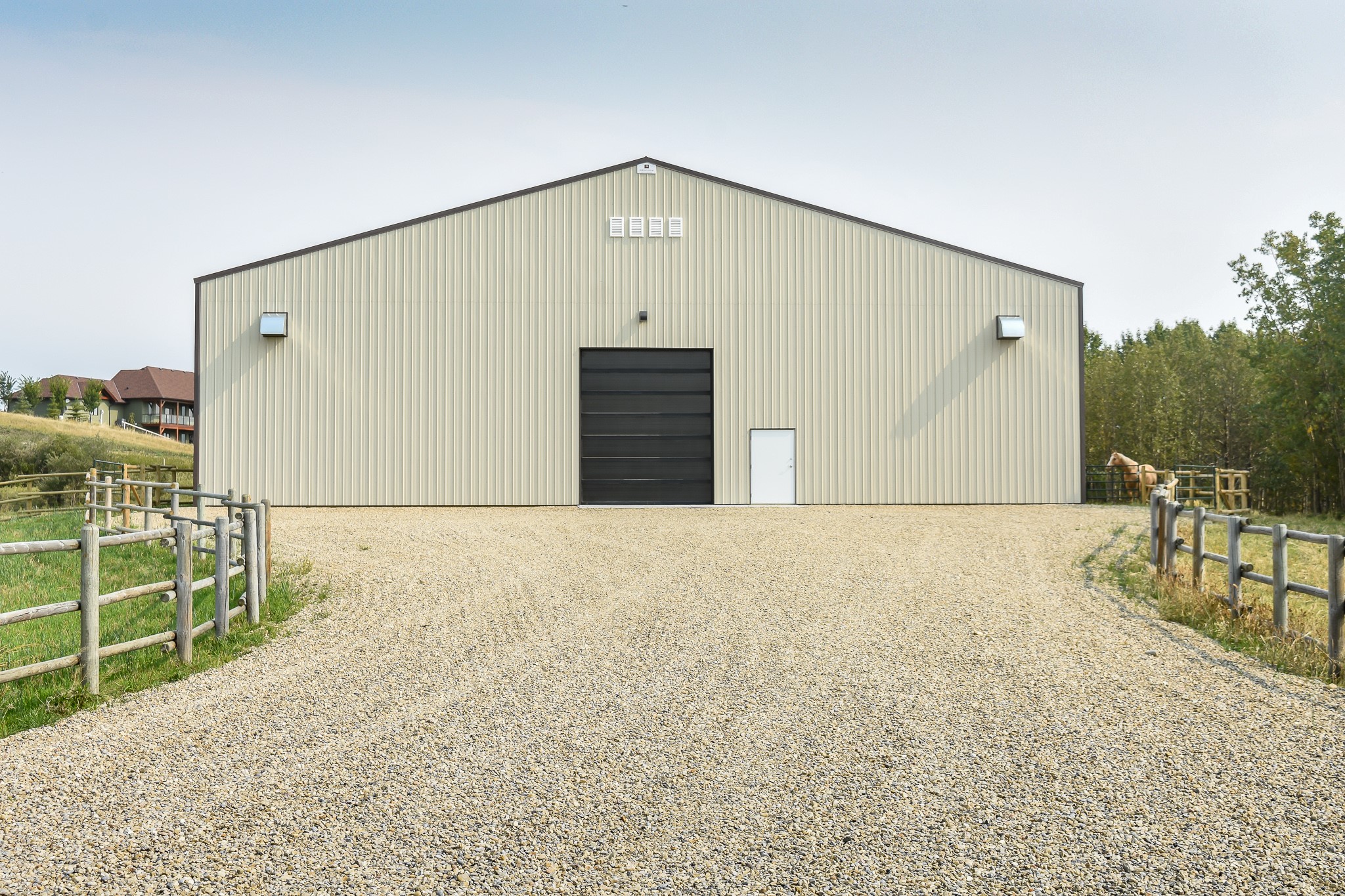 Equestrian riding arena with horse stalls shown from outside. Designed for comfortable year-round use and to enhance the well-being of horses