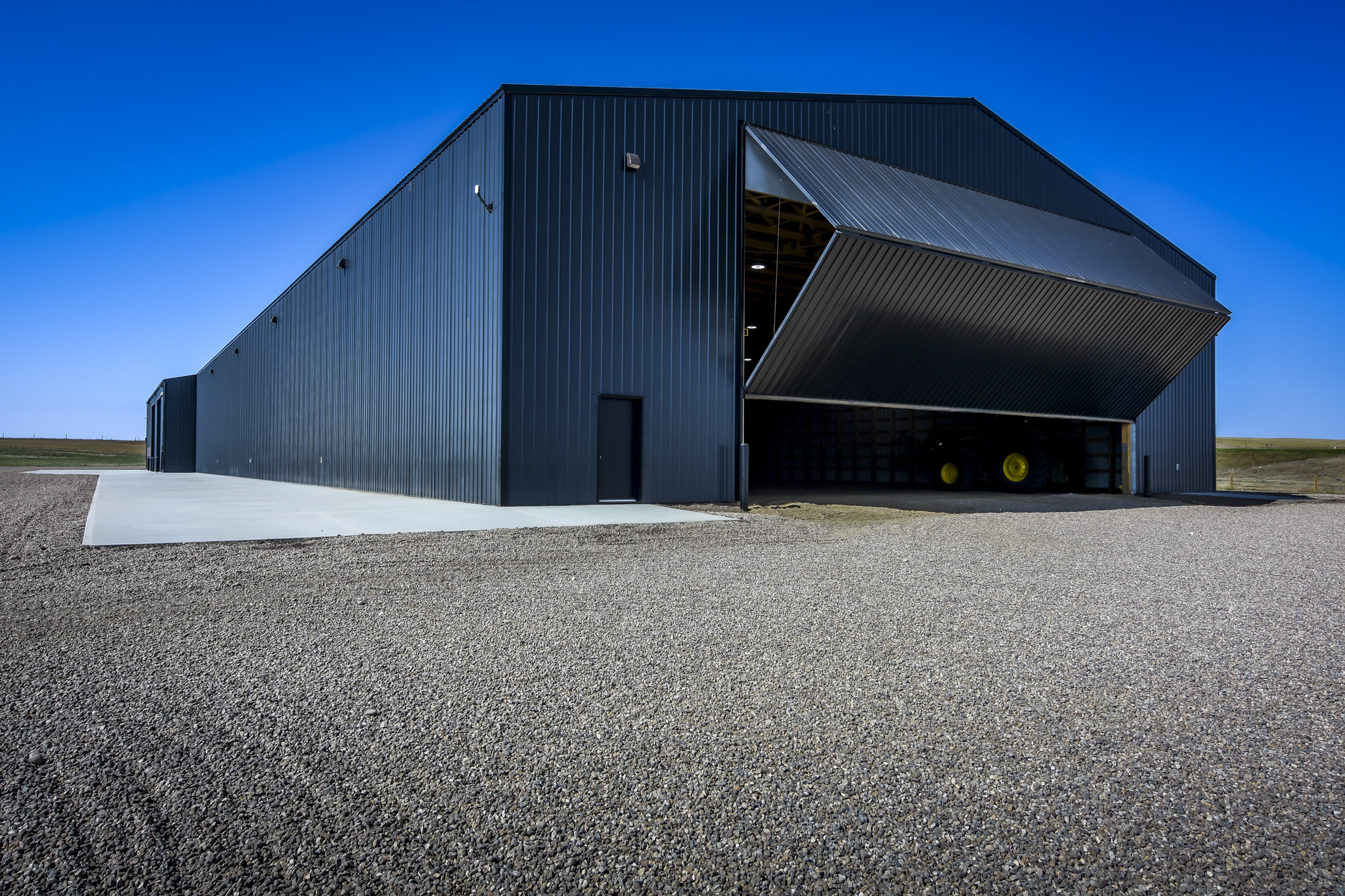 A partially opened bi-fold door on a agricultural machine shed.