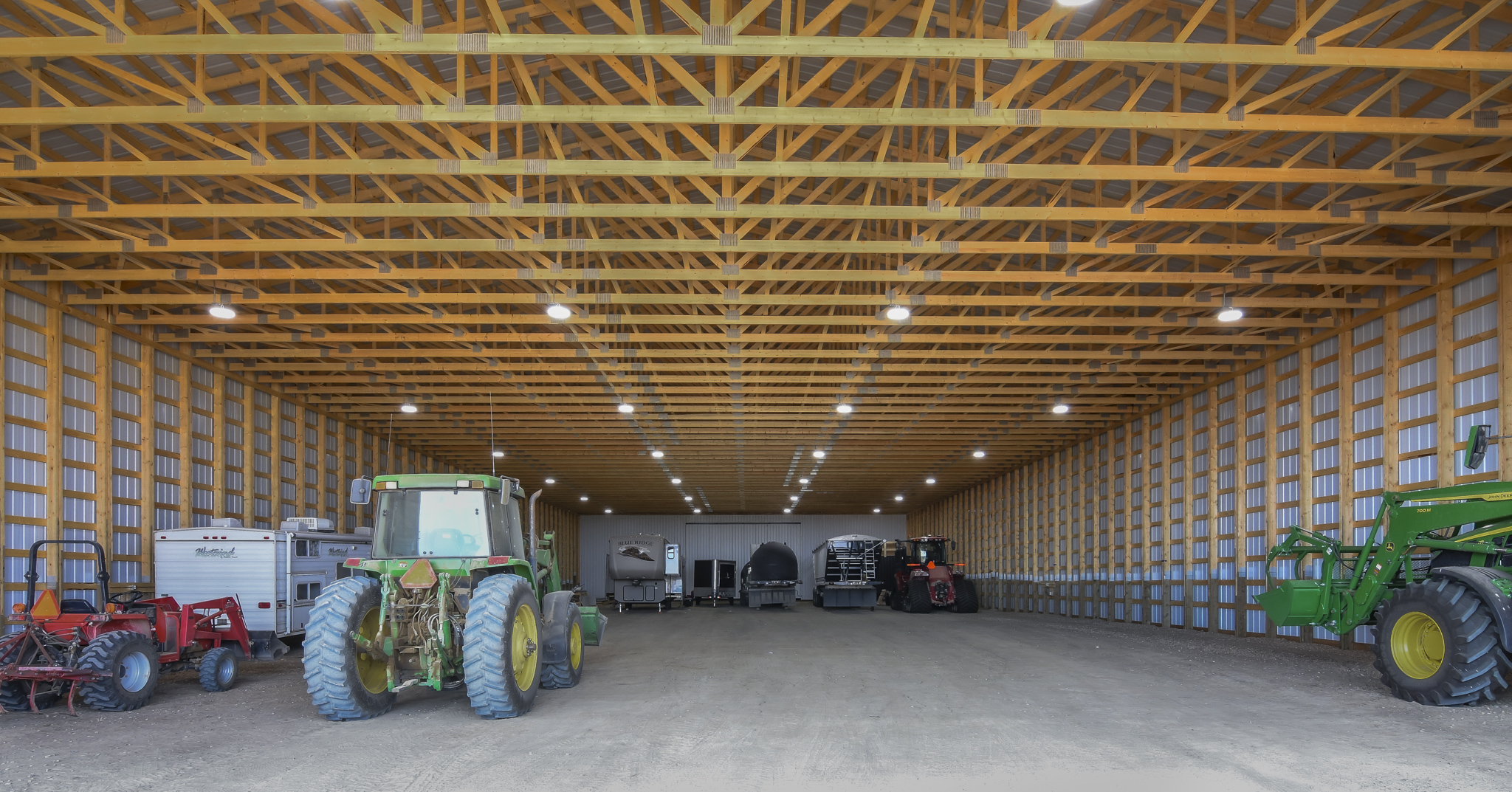 The unfished interior of a machine shed. filled with tractors and other farm equipment.