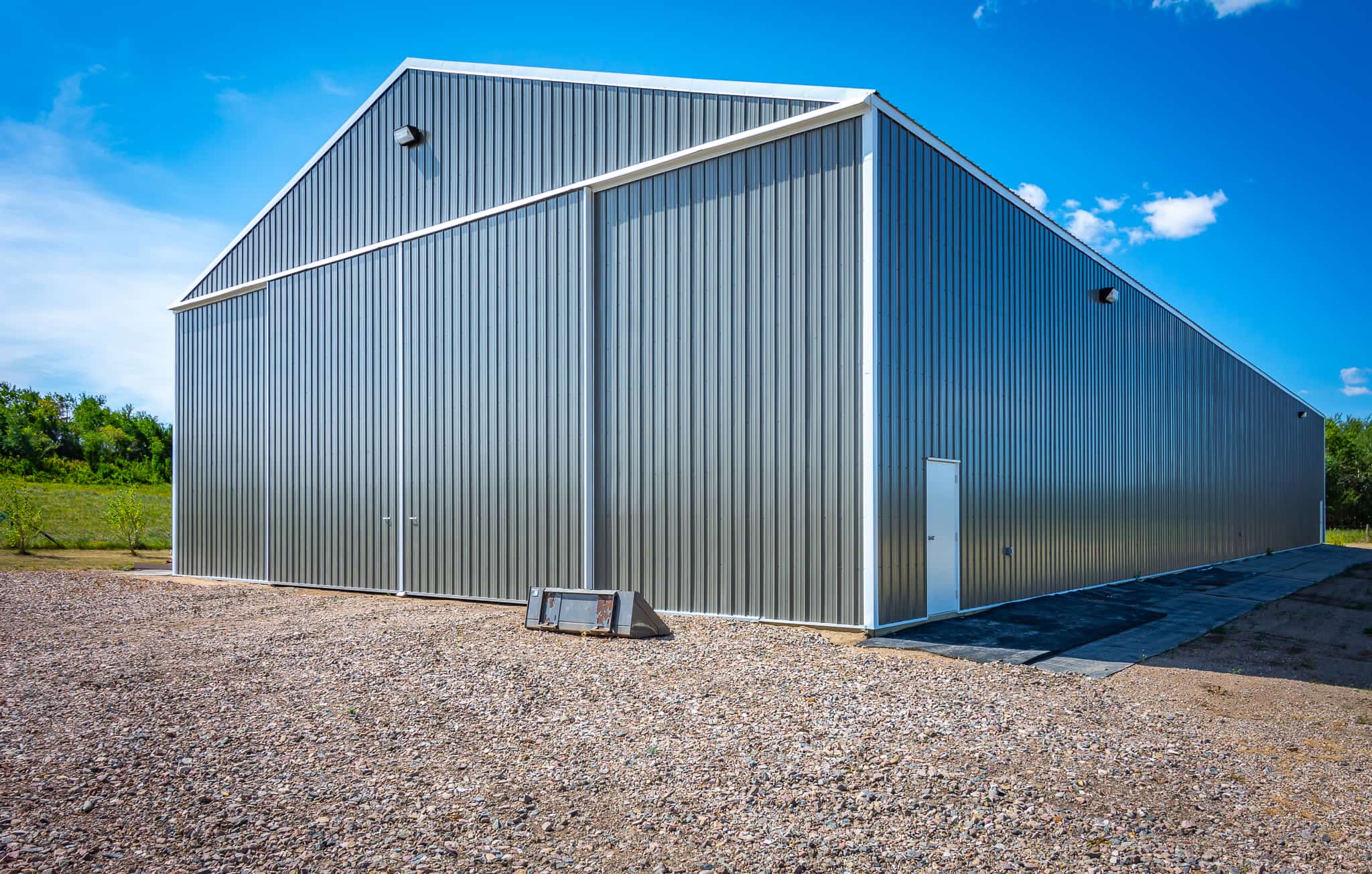 Post frame building with bi-parting sliding doors for easy equipment access