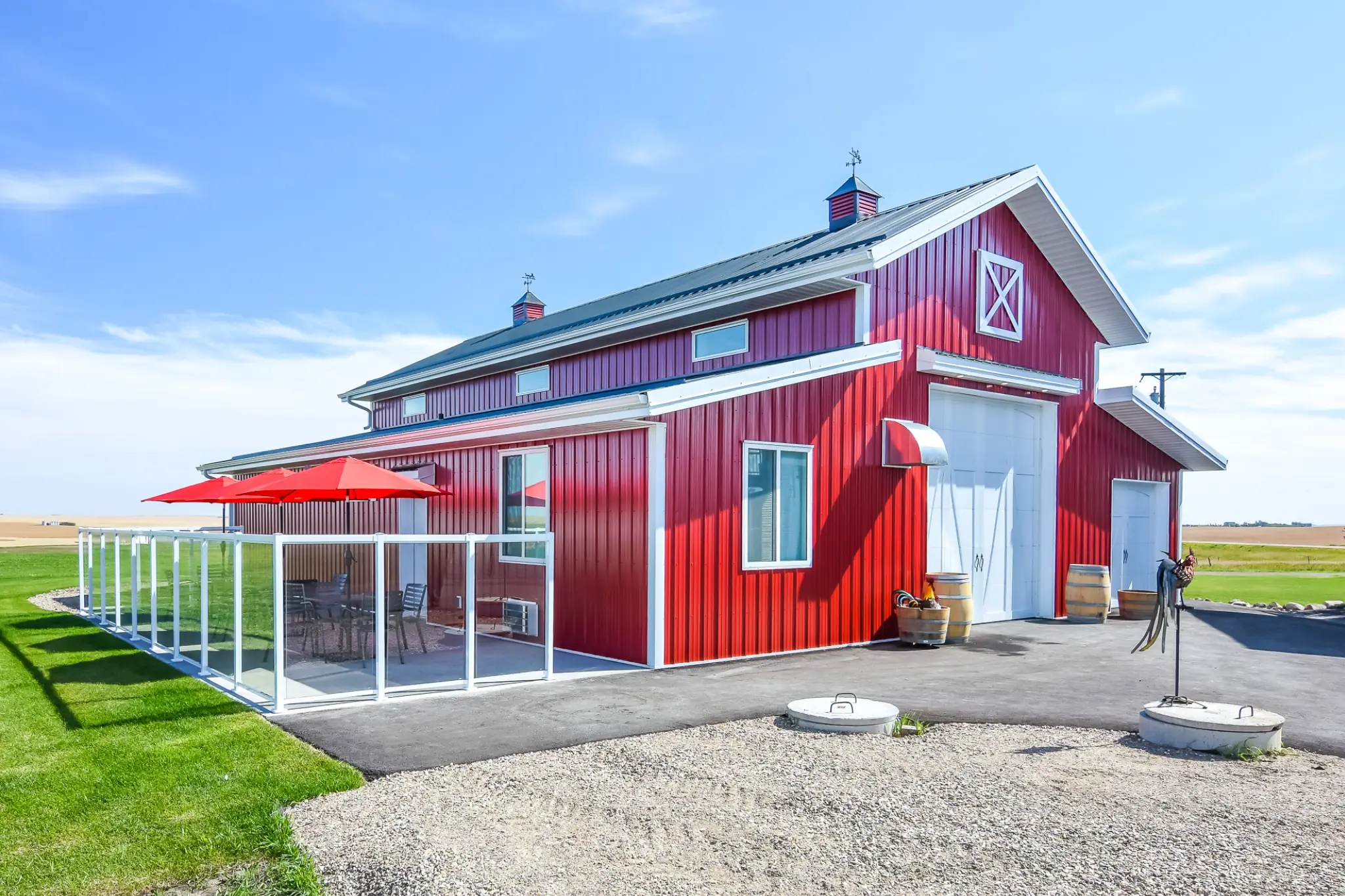 A custom monitor hobby shop with premium exterior features that include cupolas, a faux hay door, carriage doors, and an outdoor seating area