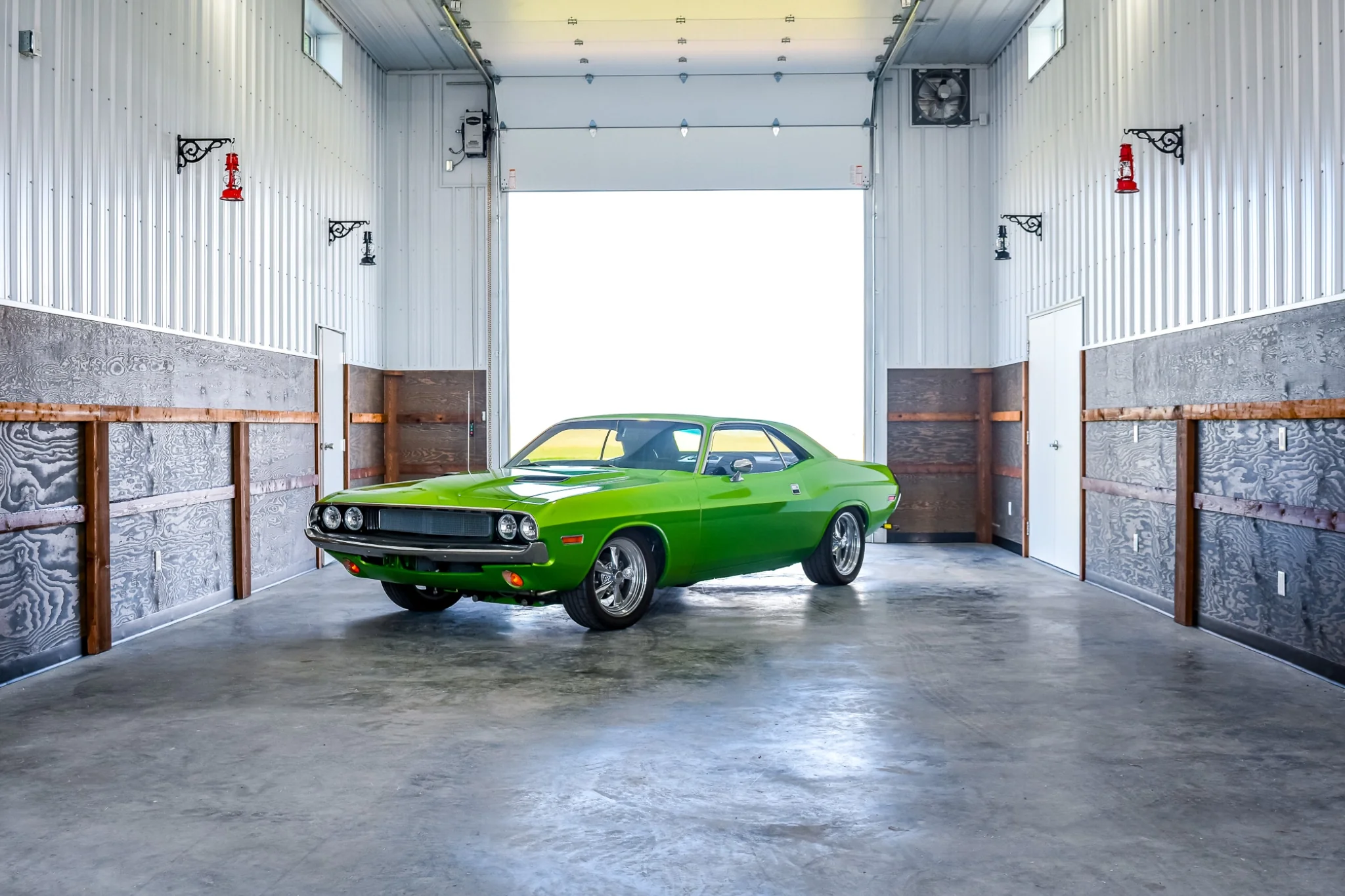 A classic green sportscar sits inside the fully finished interior of a post frame monitor-style hobby shop