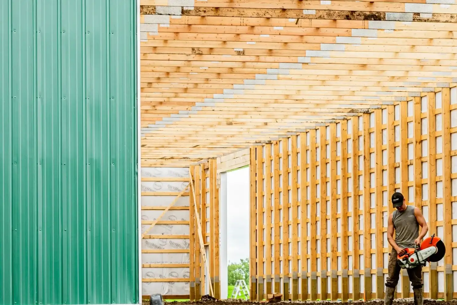 A Remuda Building crew member working on the construction of a modern post frame riding arena.
