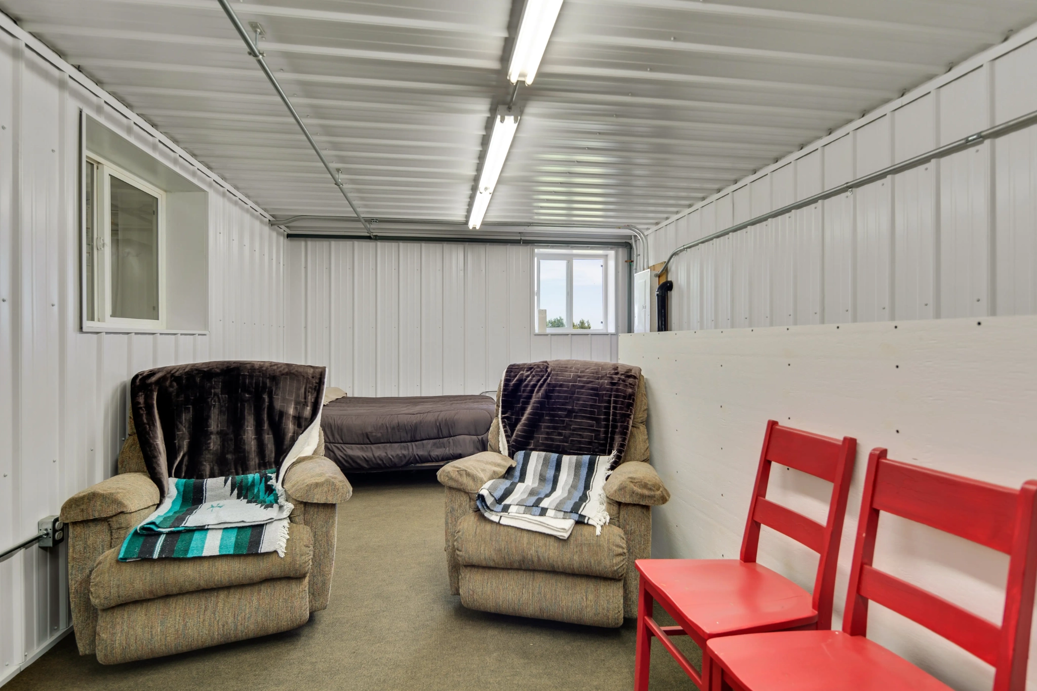A second-floor living quarters inside a calving barn with bed and chairs.