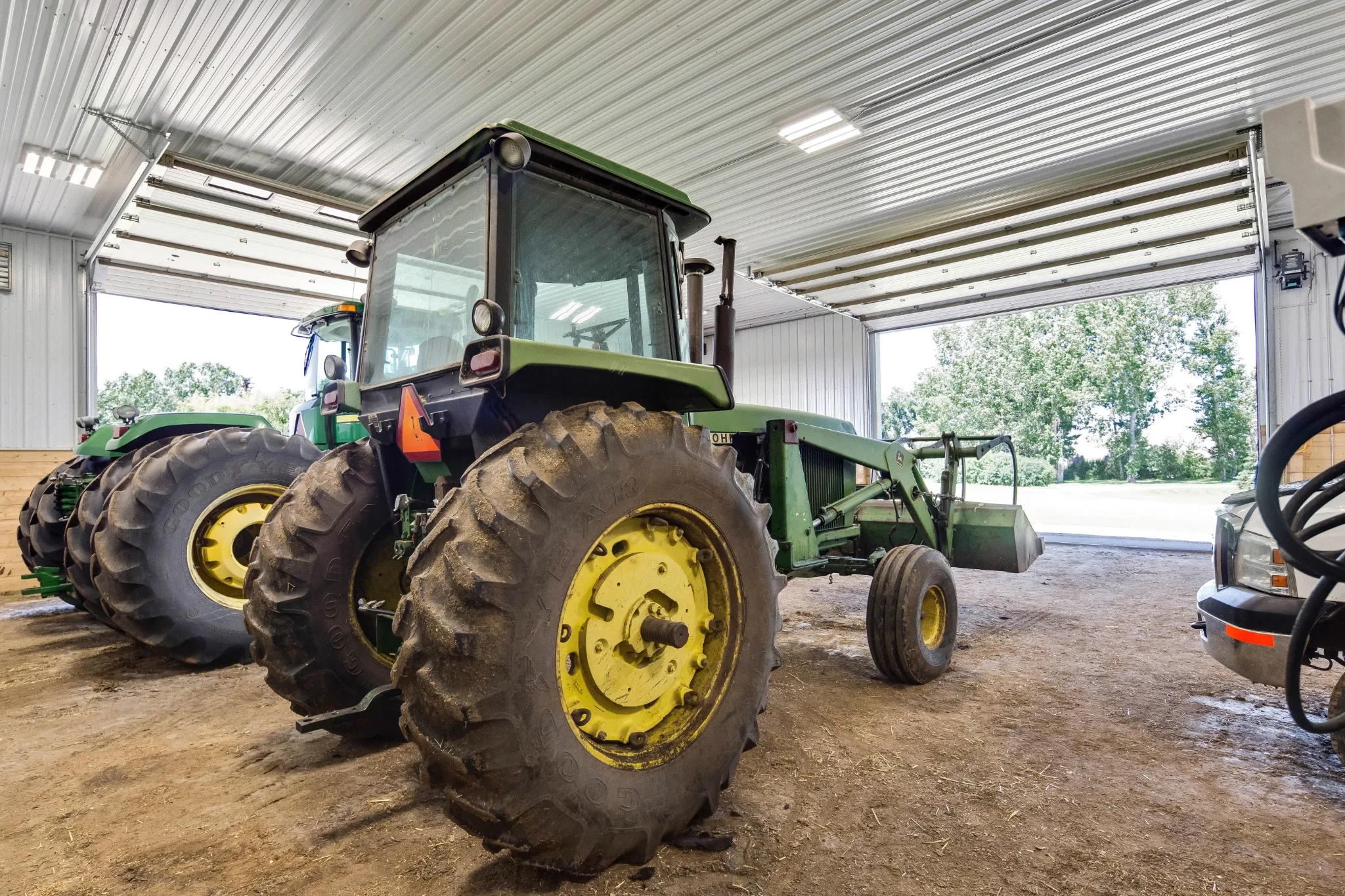 Tractors and other farm equipment sit inside a post frame farm building.