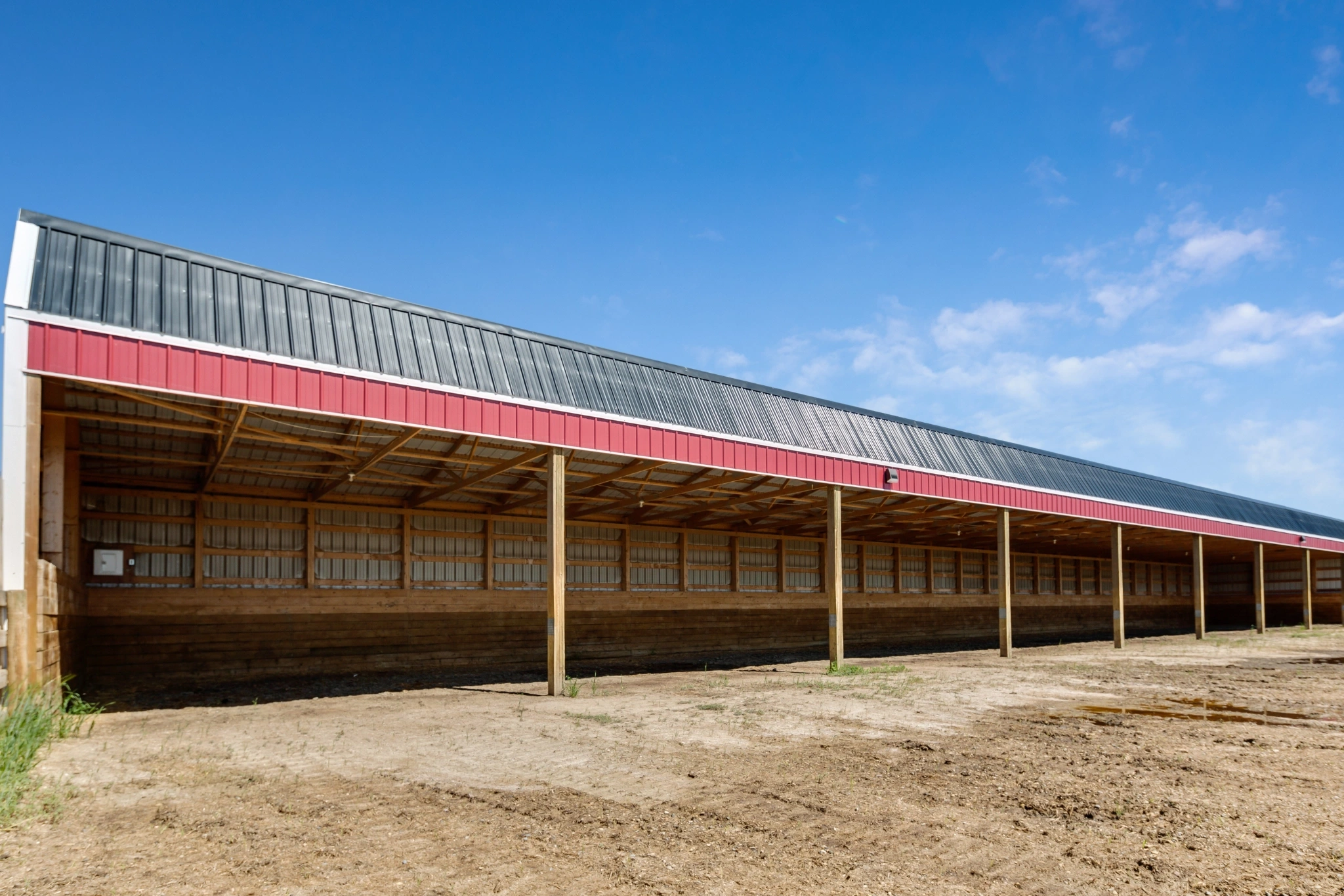 A red and black open-sided cattle shelter.