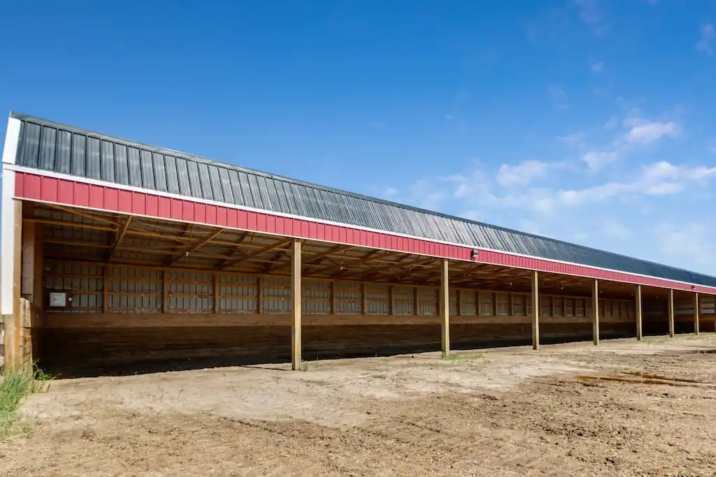 A red and black open-sided cattle shelter.