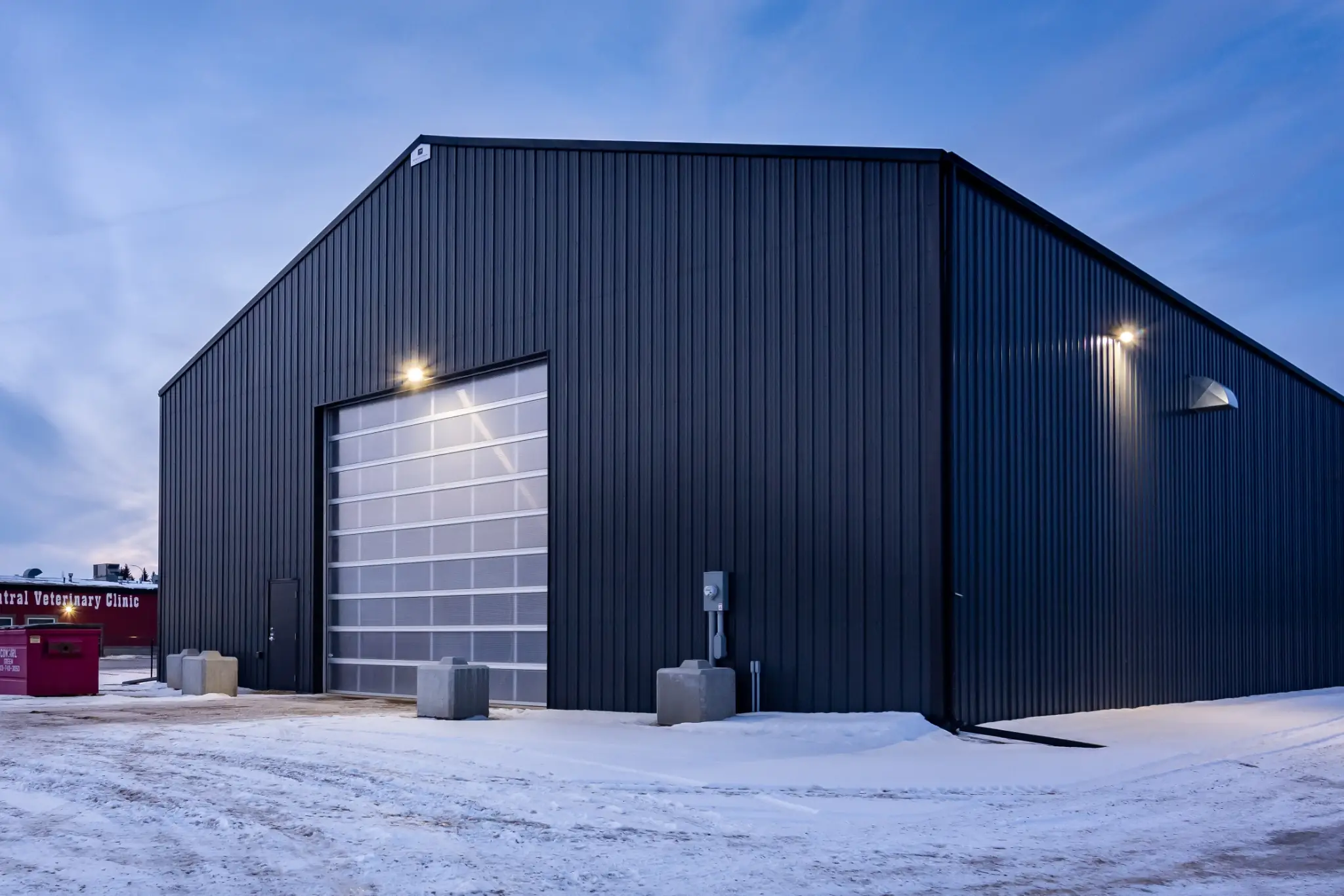 Agricultural building during dusk with exterior lights shining.