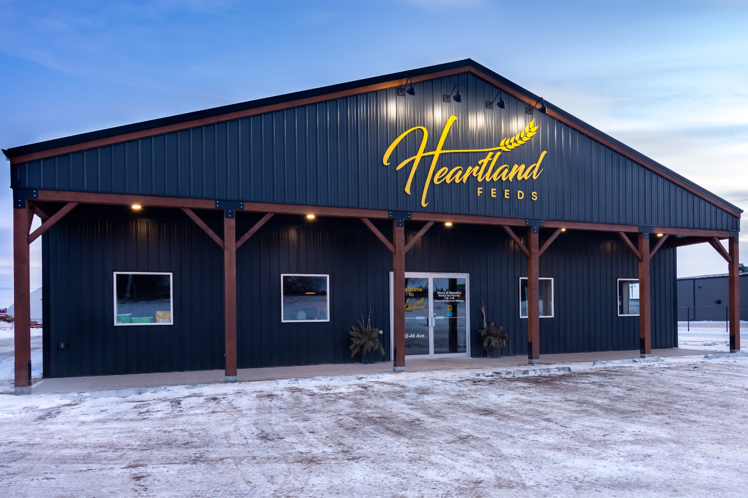 The front of a charcoal coloured post frame build during winter.