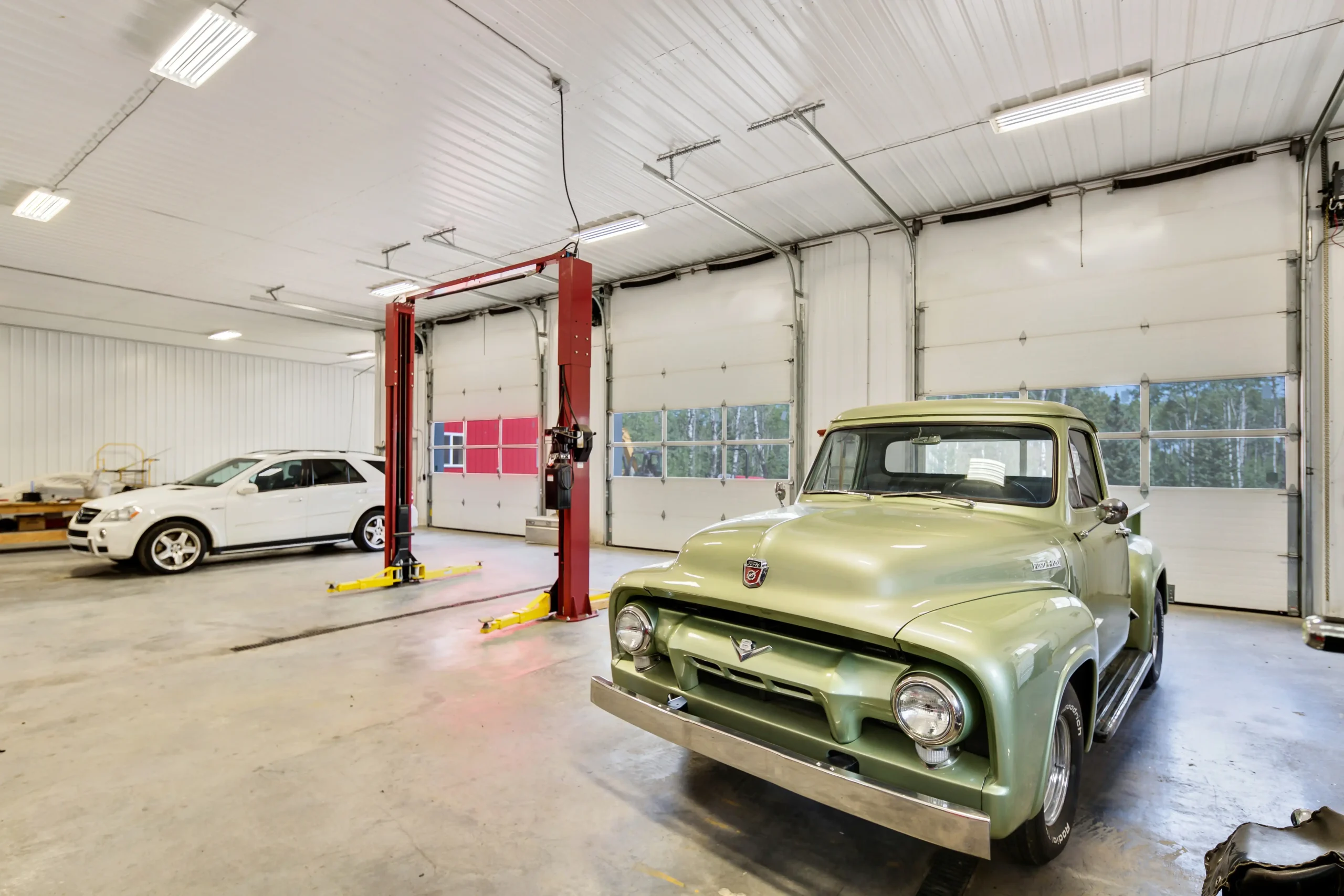 Interior of L shaped 4 garage with 4 bays and overhead doors with transparent panels to bring in daylight.