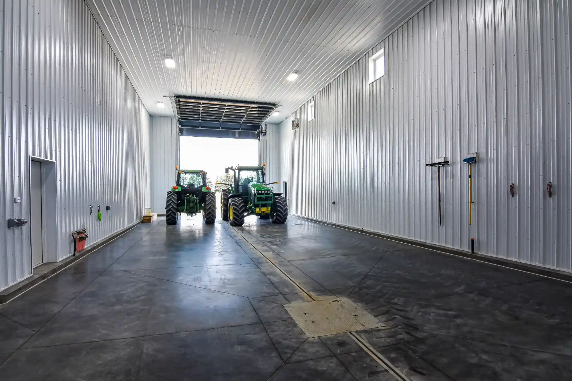 Farm equipment parked in a building with a concrete floor