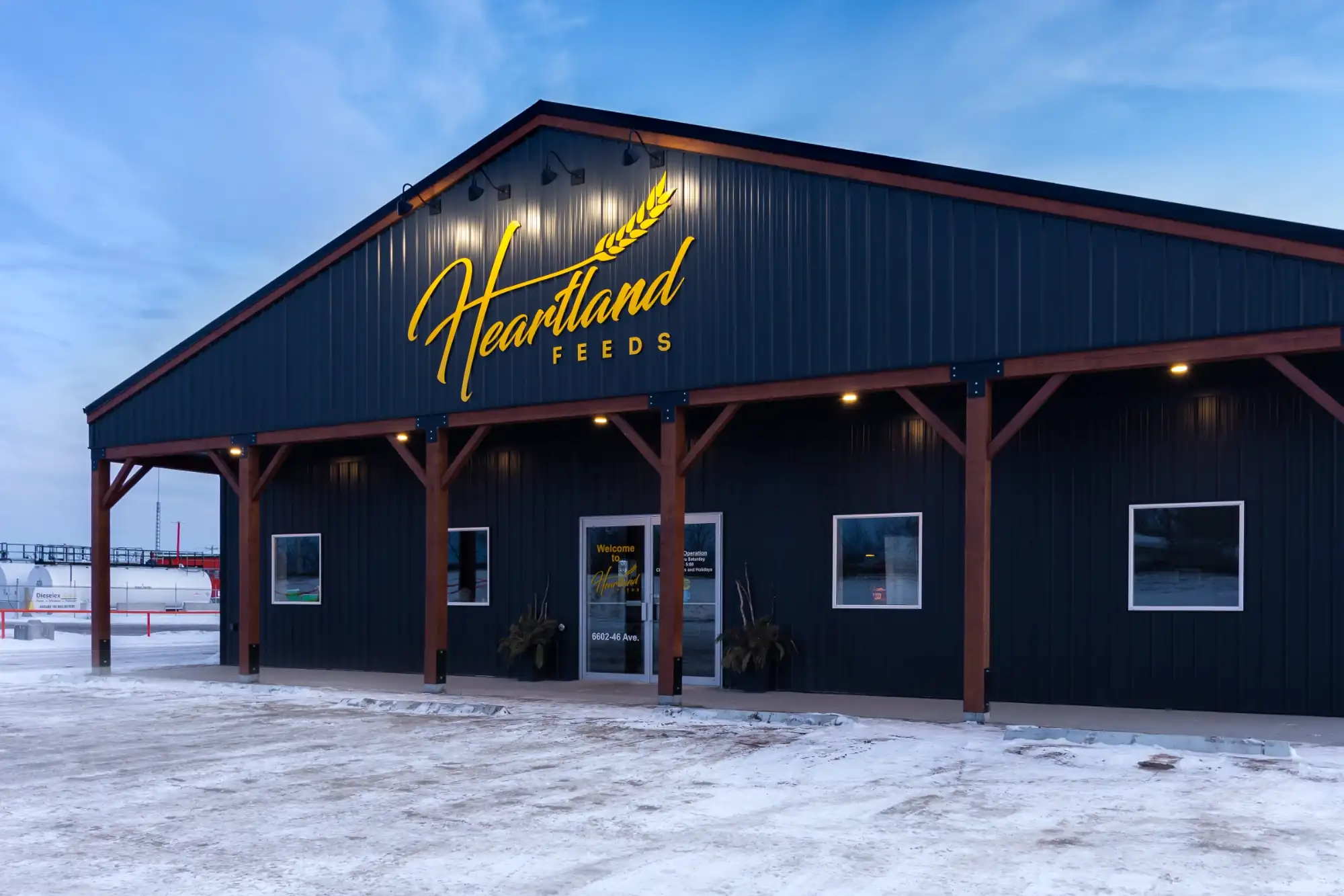 Exterior lighting shines bright on the signage of a shop built with an all in one post frame construction service.