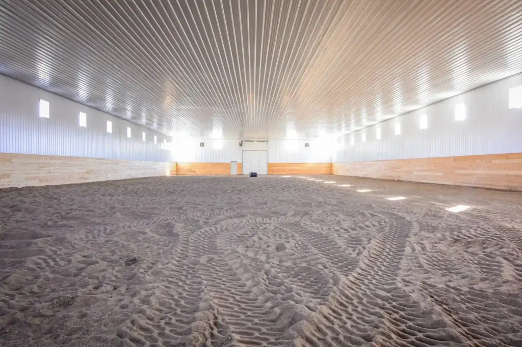 Indoor Riding Arena With Sand Footing, Metal Walls, And Kick Wall