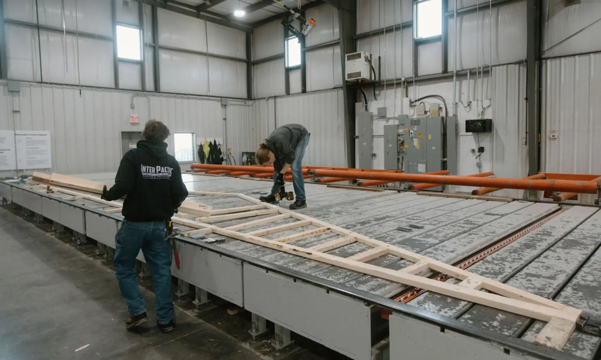 Wooden roof truss being fabricated in a truss manufacturing facility by two workers